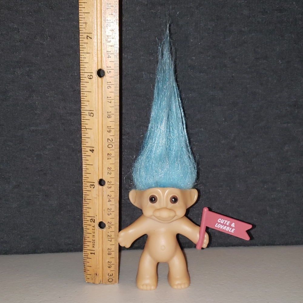 Russ troll doll with a "CUTE & LOVABLE" flag